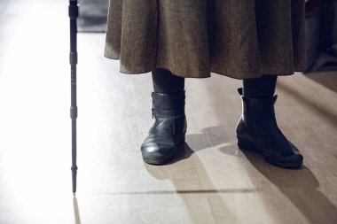 Emekli bir kadın bir baston yaslanmış durumda.