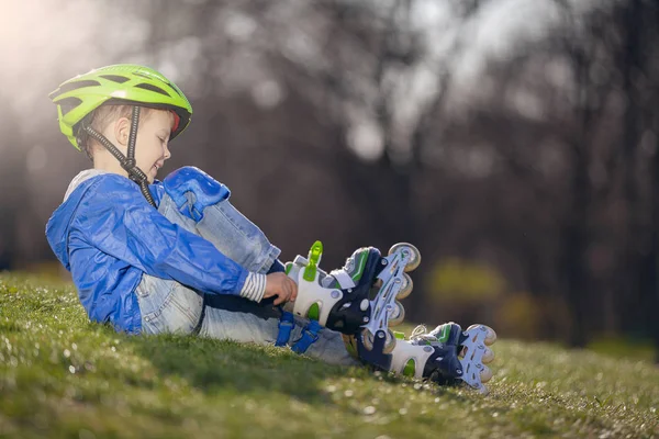 Atletizm çocuk yolculuktan önce silindirlerde çim Ayakkabı üzerinde oturuyor.