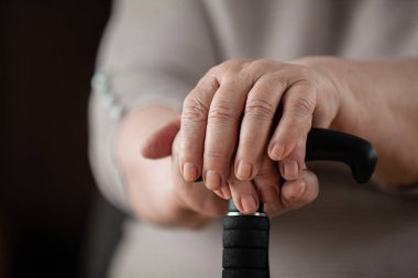 Emekli kadın, elleri ve baston yakın çekim.