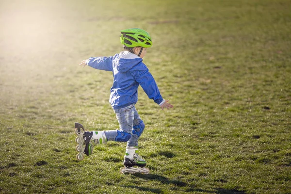 Athletic boy riding on the grass on the rollers in sunny weather.