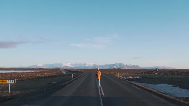 Chica viajero en un camino vacío en el fondo de las montañas — Vídeos de Stock