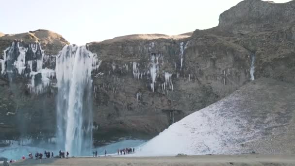 Ett kluster av turister nära vattenfallet vinter — Stockvideo