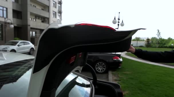 Чоловік закриває кришку багажника автомобіля — стокове відео