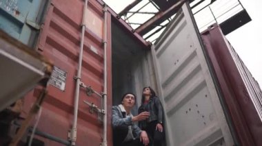 Kapsayýcý içinde oturan genç adam sigara içiyor