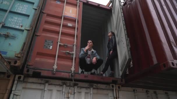 貨物コンテナーに座っている若い男を吸う — ストック動画