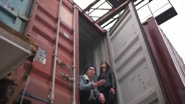 Хлопець курить, сидячи в контейнері — стокове відео