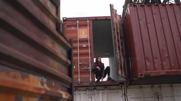 Дівчина в джинсових сидять в контейнері — стокове відео
