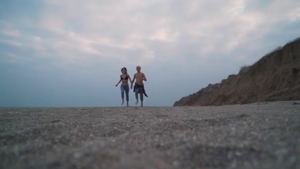 pár v džínové běžící na pláži