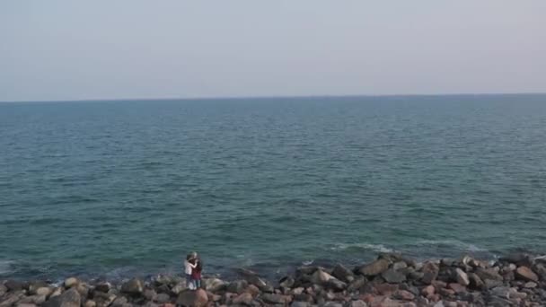 Pareja de pie en las rocas junto al mar — Vídeos de Stock