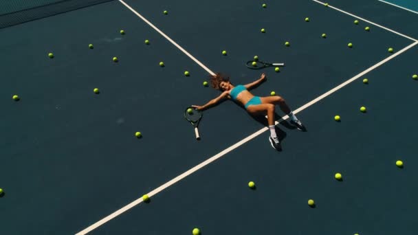 Dívka s tenisovými míčky leží na kurtu — Stock video