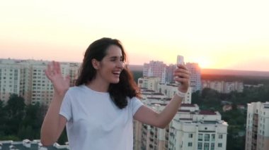 Kız yanında bir binanın çatısında smartphone iletişim kurar