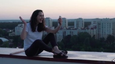 Kız yanında bir binanın çatısında smartphone iletişim kurar