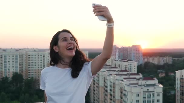 Chica se comunica por teléfono inteligente en la parte superior de un edificio — Vídeos de Stock
