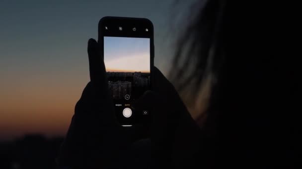 Chica toma fotos en el teléfono inteligente al atardecer — Vídeos de Stock