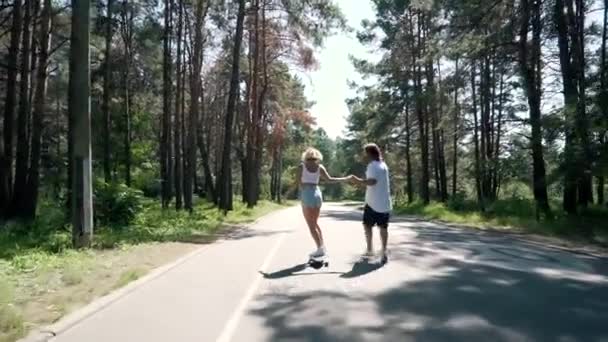 Парень держит девушек за руку, когда она ездит на скейтборде — стоковое видео