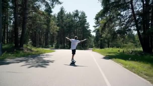 Een jongen rijdt een skateboard op een lege weg — Stockvideo