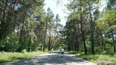 bir adam parkta boş bir yolda bir kaykay sürmek.