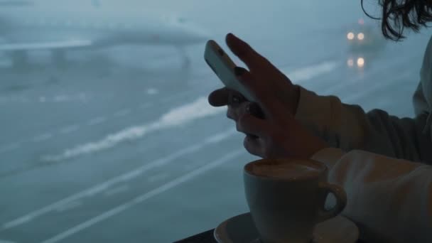 Flicka med kaffe och smartphone i flygplatslounge — Stockvideo