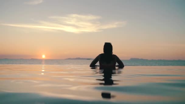 Девушка расслабляется в бассейне на закате — стоковое видео