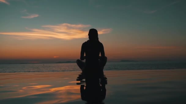Kız okyanusa bakan gün batımında meditasyon — Stok video