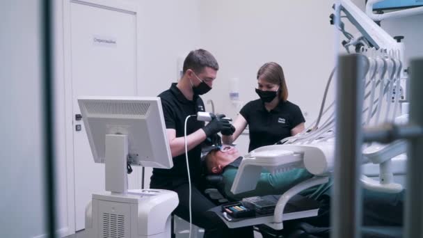 Dentist and assistant do an operation for a patient — Stock Video