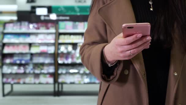 Девушка пользуется телефоном в магазине крупным планом — стоковое видео