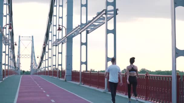Αθλητικό ζευγάρι περπατά στη γέφυρα — Αρχείο Βίντεο