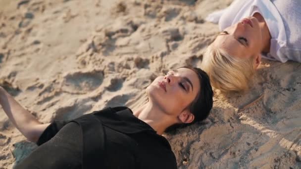 Kızlar kumda yatarken meditasyon yaparlar. — Stok video