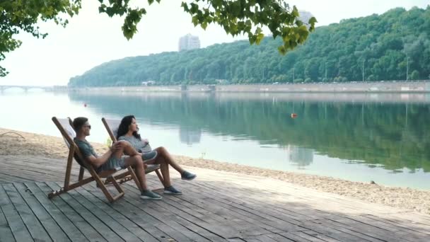 Par slappnar av vid floden i en metropol — Stockvideo