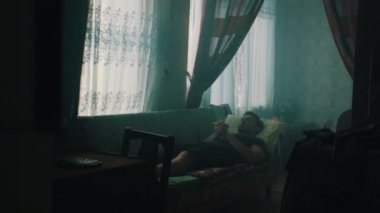 Bir adam eski bir SSCB dairesinde dinleniyor.