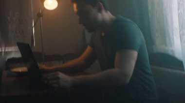 Adam evde otururken dizüstü bilgisayarda iş arıyor.
