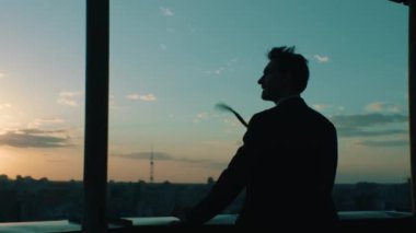 İş adamı gün batımında şehre tepeden bakıyor.