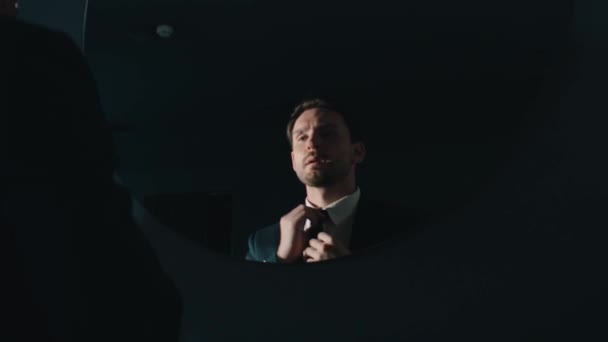Мужчина выпрямляет галстук в зеркале — стоковое видео