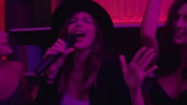 Kızlar neon ışıklarıyla gece kulübünde karaoke yaparlar.