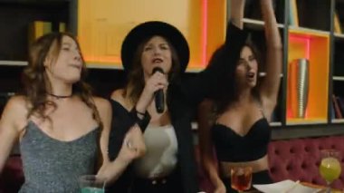 Kızlar gece kulübünde eğleniyor ve karaoke yapıyor.