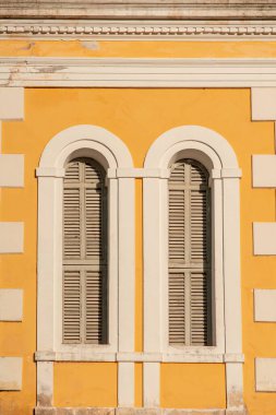 Parlak sarı duvardaki iki kemerli pencerenin mimari ayrıntıları