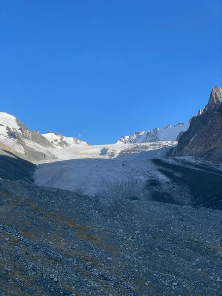 Berrak mavi gökyüzünün altında kayalık vadiden uzanan devasa bir buzul..