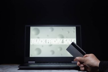 Kara Cuma indirimli gri reklamı olan ve ödeme güvenlikli bir bilgisayar ekranını gösteren kredi kartı olan bir kişi.