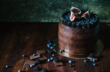 Taze yabanmersini, böğürtlen ve rustik koyu arka plan üzerinde incir ile çikolatalı kek