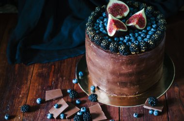 Taze yabanmersini, böğürtlen ve rustik koyu arka plan üzerinde incir ile çikolatalı kek