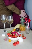 Ein Paar trinkt Champagner mit liegenden Erdbeeren und exotischen Früchten. Valentinstag. Romantischer Abend.