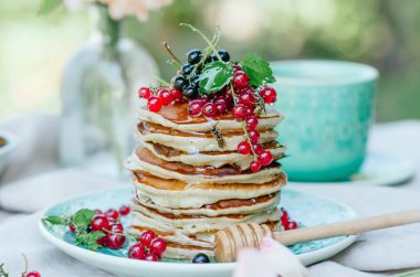 Taze meyveleri ve ballı kahvaltı için mavi bir plaka üzerinde muz krep yığını