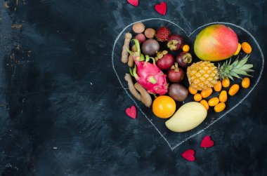 Koyu arka plan üzerinde egzotik tropik meyve yürekten. Ananas, mango, tutku meyve, demirhindi, granadilla, Kamkat, lychee, pitahaya, rambutan. Düz yatıyordu.
