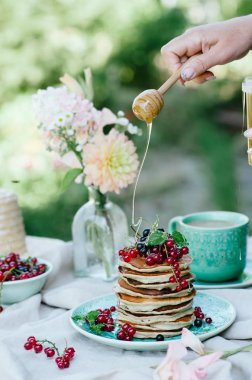 Taze meyveleri ve ballı kahvaltı için mavi bir plaka üzerinde muz krep yığını