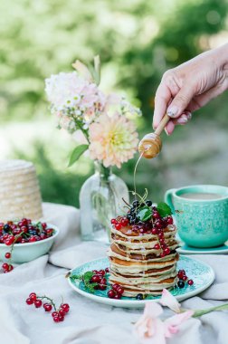 Taze meyveleri ve ballı kahvaltı için mavi bir plaka üzerinde muz krep yığını