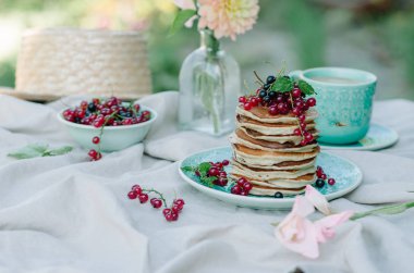 Taze meyveleri ve ballı kahvaltı için mavi bir plaka üzerinde muz krep yığını