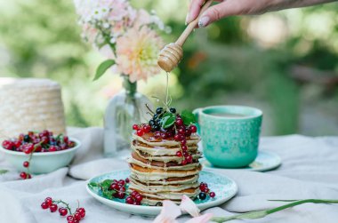 Taze meyveleri ve ballı kahvaltı için mavi bir plaka üzerinde muz krep yığını