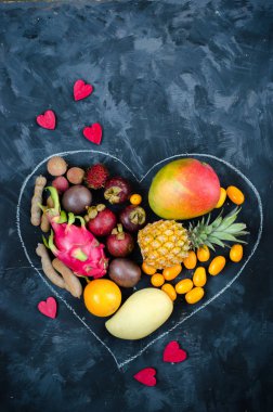 Koyu arka plan üzerinde egzotik tropik meyve yürekten. Ananas, mango, tutku meyve, demirhindi, granadilla, Kamkat, lychee, pitahaya, rambutan. Düz yatıyordu.