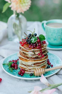 Taze meyveleri ve ballı kahvaltı için mavi bir plaka üzerinde muz krep yığını