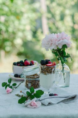 Kadının eller sağlıklı kahvaltı yediği gibi. Çilek ve granola masanın üzerine bir kase yoğurt.